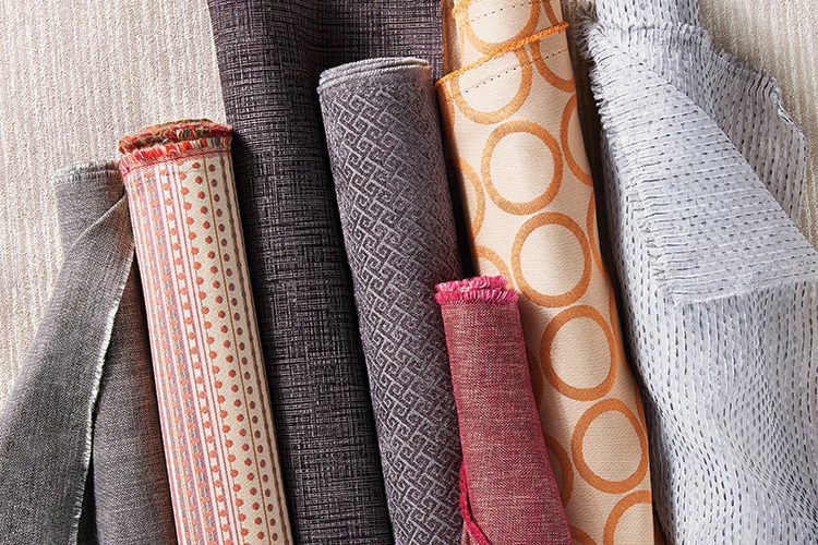 Rolls of hospitality fabrics bolts featuring a variety of colors and patterns are shown here.