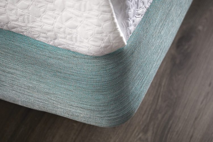 A close up image of the corner of a hotel bed featuring a Pivot/Tourmaline box spring cover.