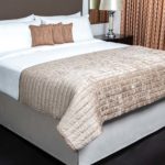 Custom Top of Bed and Bed Skirt: Pillows in Nova/Terra Cotta; Quilted Image of a made bed with Throw in Jewel/Pewter; Top Cover in Savannah/White; Headboard in Montauk/Mocha; Bed Skirt in Zircon/Porpoise