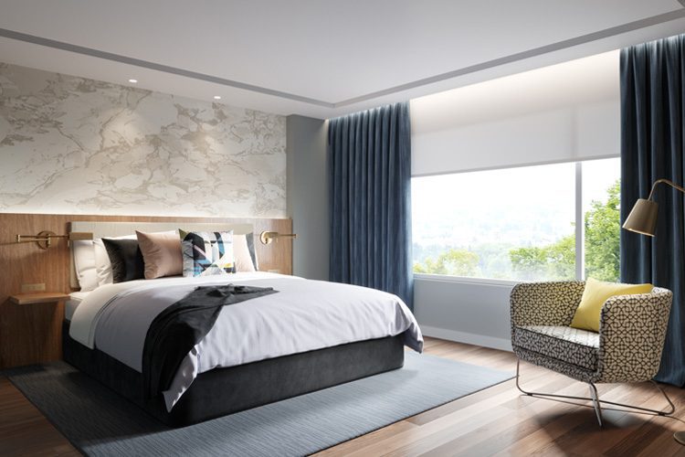 A hotel guest room featuring a bed, chair, and large, floor-to-ceiling curtains.