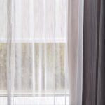A detail shot of a window featuring a Dynamo window sheer and portier drapery.