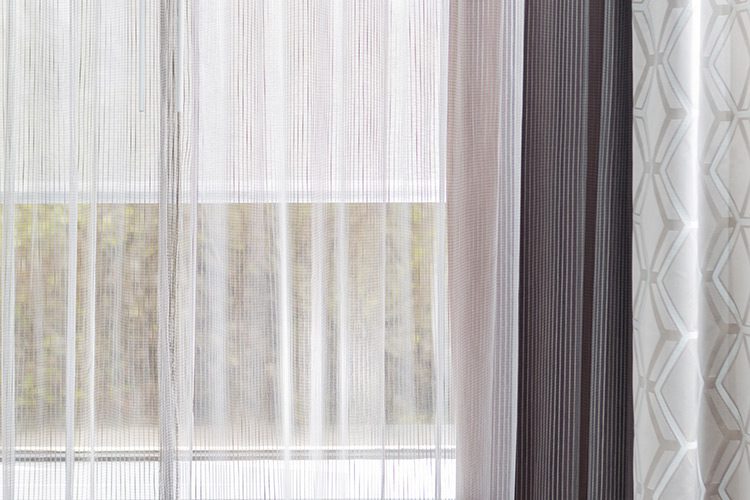 A detail shot of a window featuring a Dynamo window sheer and portier drapery.