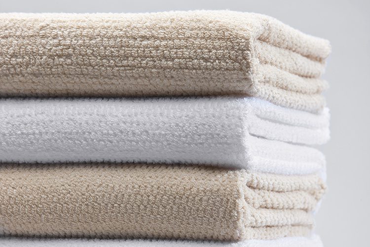A stack of Lynova blankets in white and champagne.