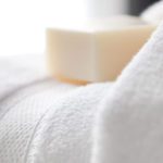 A stack of Lynova bath towel with an artisan bar of soap on top.