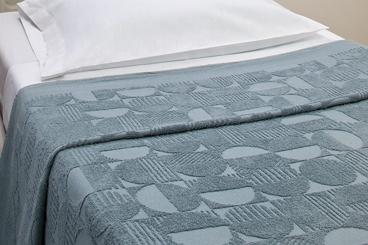 A patient bed featuring a Spa Blue color Moonphase hospital blanket | Hospital Blankets & Spreads