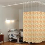 On The Right Track Privacy Curtains shown in the pattern Blocks in color-way Tahiti are shown hanging around a bed in a hospital room.