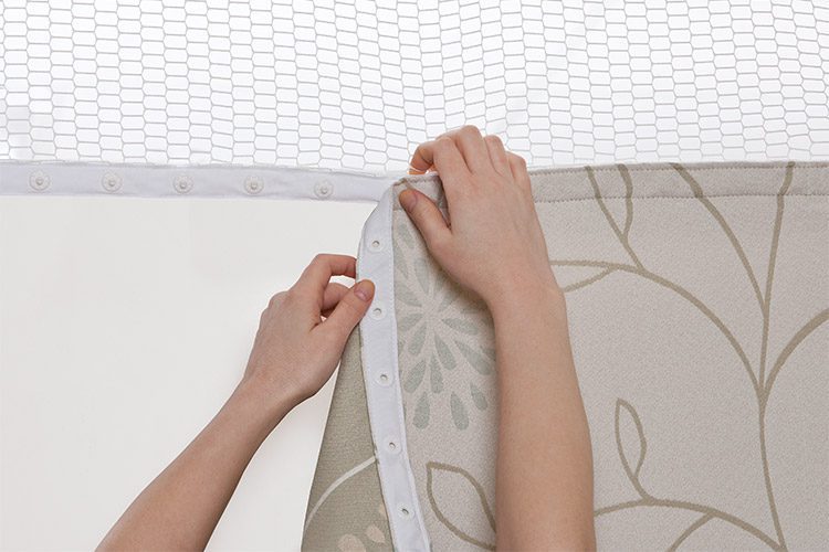 Hands snapping a removable healthcare / hospital privacy curtain into place.