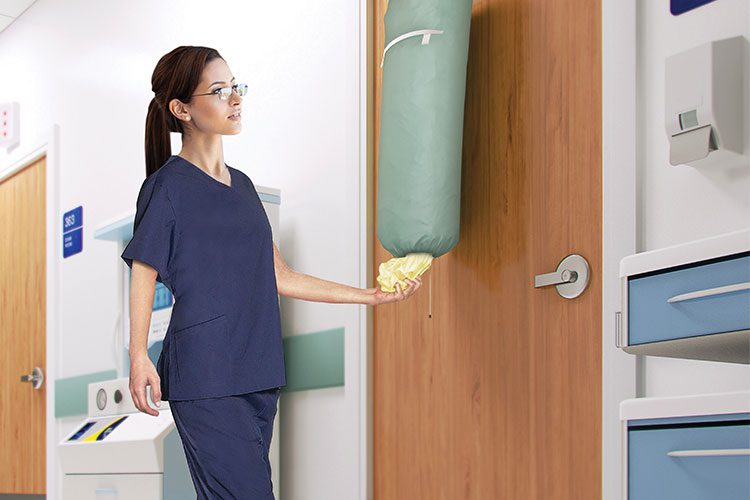 A nurse removing a PreCaution Gown from a PreCaution Gown Dispenser bag.