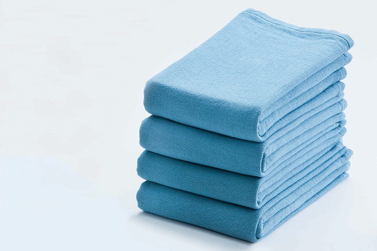 A stack of four folded SofSorb Surgical Towels. These are reusable surgical towels.