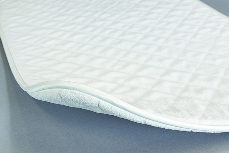 A SoftStep bath mat laying on a grey surface.