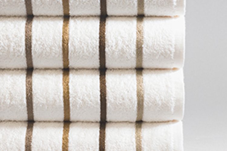 Stack of white pool towels with brown and beige stripes.