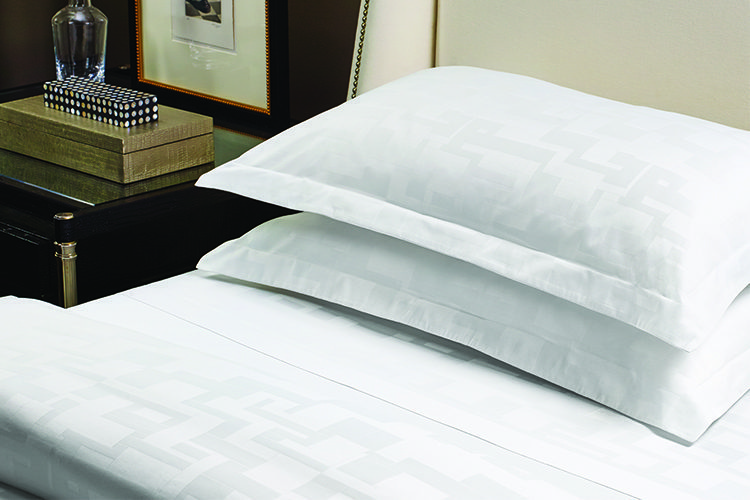 Two pillows on hotel bed made with TAL Designer Sheets in Braque.