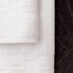 An image of TAL Braque terry towel and handtowel hanging in a bathroom.