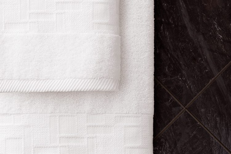 An image of TAL Braque terry towel and handtowel hanging in a bathroom.