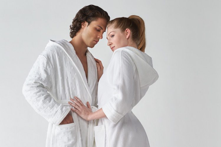A man and a woman posing together, both are wearing Heidi Weisel bath robes.