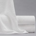 A Gradient bath towel draped over a stack of two folded Gradient bath towels.
