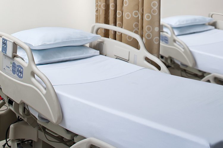 This image is a patient's room showing a hospital bed made with Blue UniVal sheets.