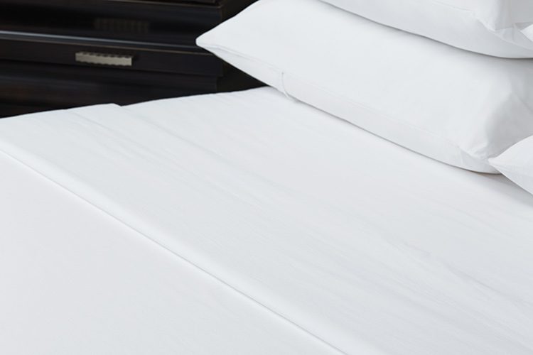 Pillow and bed dressed with luxury Vidori sheets for hotels