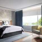 A luxury hotel guest room featuring a well made bed and a large wall-to-wall window with a scenic view.