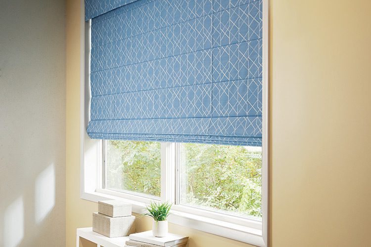 Photo of a blue roman shade hanging in a window.