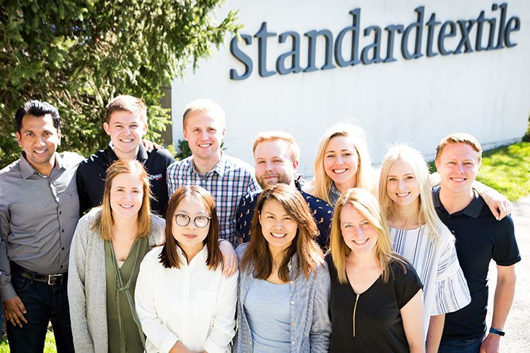 A group photo of Standard Textile employees posing in front of the Standard Textile headquarters in Cincinnati, Ohio.