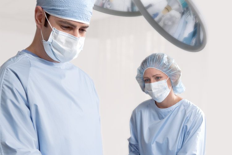 Two surgeons wearing blue Compel Surgical Gowns.