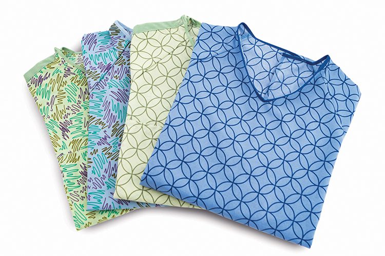 A fanned pile of four folded E*Star patient gowns, each a different pattern and color.