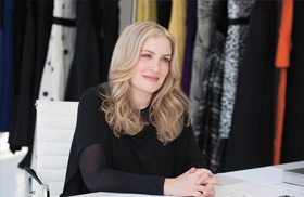 Designer Heidi Wiesel seated in front of a wall featuring a variety of fabrics.