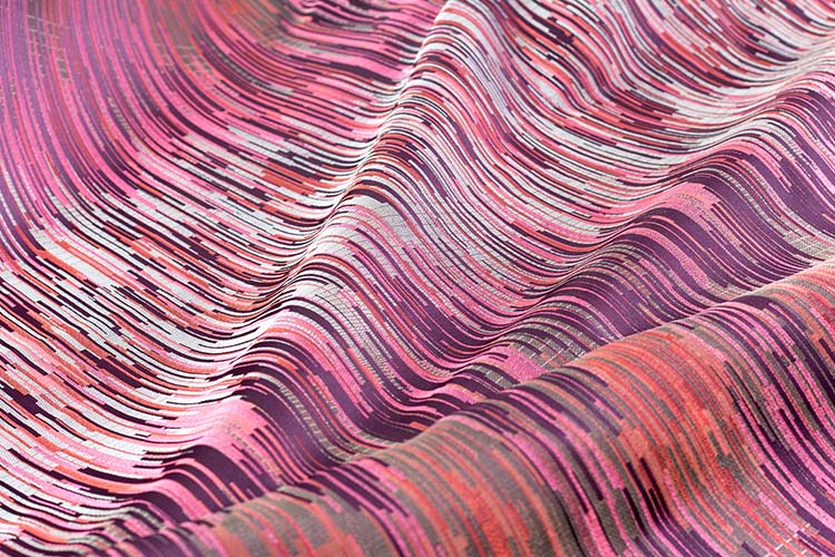 A detail shot of folds of a fabric featuring a vibrant pink and red pattern.