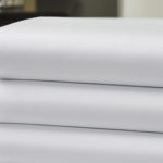 Stack of three luxury Vidori sheets in a hotel room