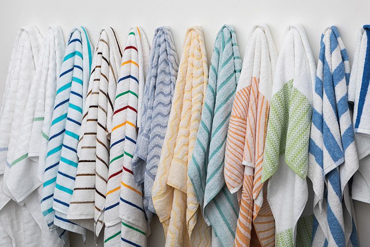 A row of pool towels hanging on a wall. The pool towels showcase a variety of vibrant colors and patterns.