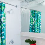 A hotel bathroom featuring a vibrant blue and green shower curtain. Our shower curtains for hotels can be made with our exclusive Impact Technology®.