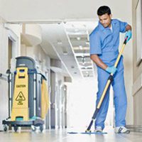 Hospital employee mopping floors wearing blue scrubs