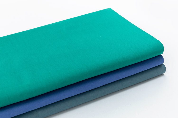A stack of three folded dyed Healthcare sheets.