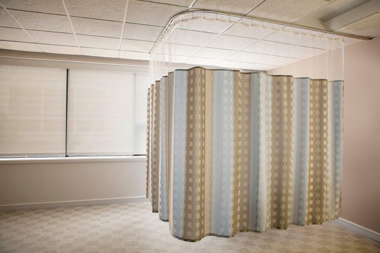 A small area of a patient room sectioned off with hospital privacy curtains.
