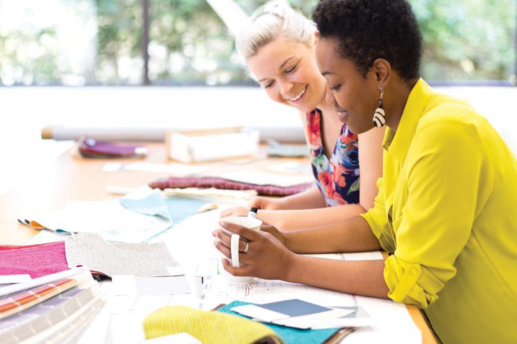 Two team members working at a table, surrounded by fabric samples and color swatches.