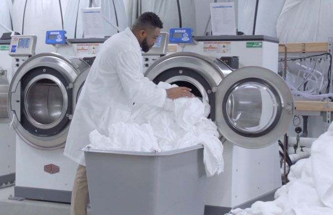 Man loading hospitality linens into an industrial washing machine