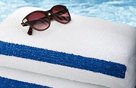 women's sunglasses on stack of striped pool towels