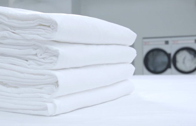 stack of clean white towels on a table in front of washer