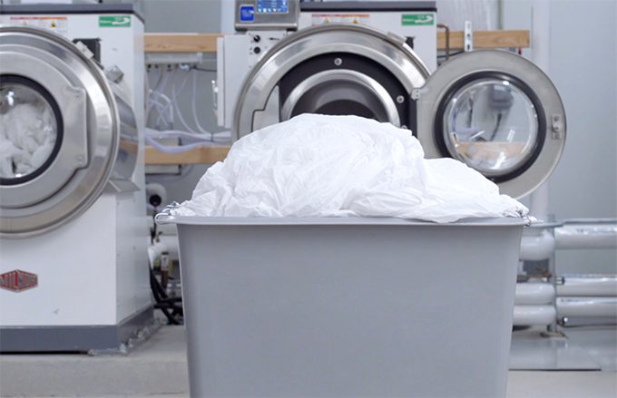 full load of laundry in a bin next to industrial dryer