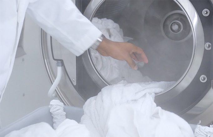 man removing clean towels from industrial washer