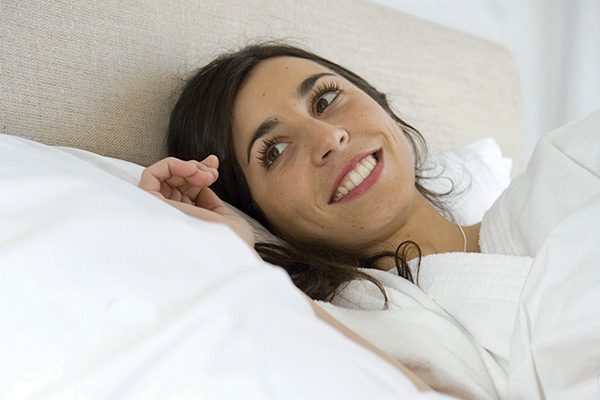 Happy woman laying in comfortable bed featuring AllerEase Products