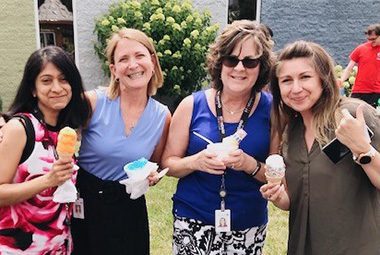 Four female associates eating ice cream at the ice cream social outside at Standard Textile.
