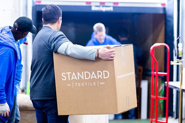 Standard Textile Home associate helping to move a box into a moving truck.