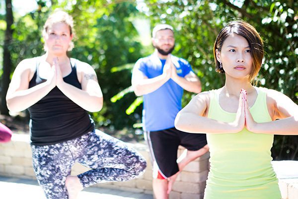 Two female associates and one male associate participating in a yoga fitness class outside at headquarters in Cincinnati, Ohio.