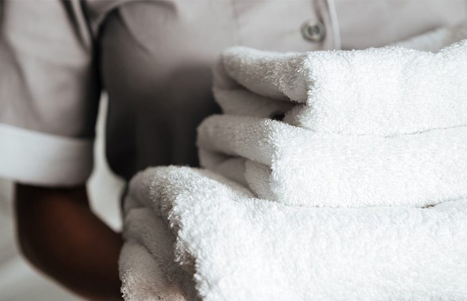 Housekeeper Holding Stack of White Towels