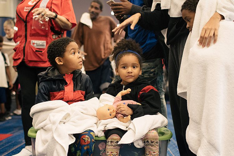 Two children holding towels at a Red Cross crisis response unit