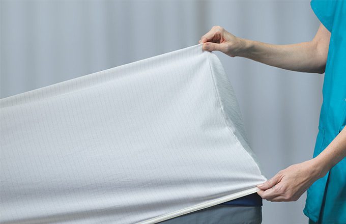 Nurse putting DermaTherapy® sheets on a hospital bed.