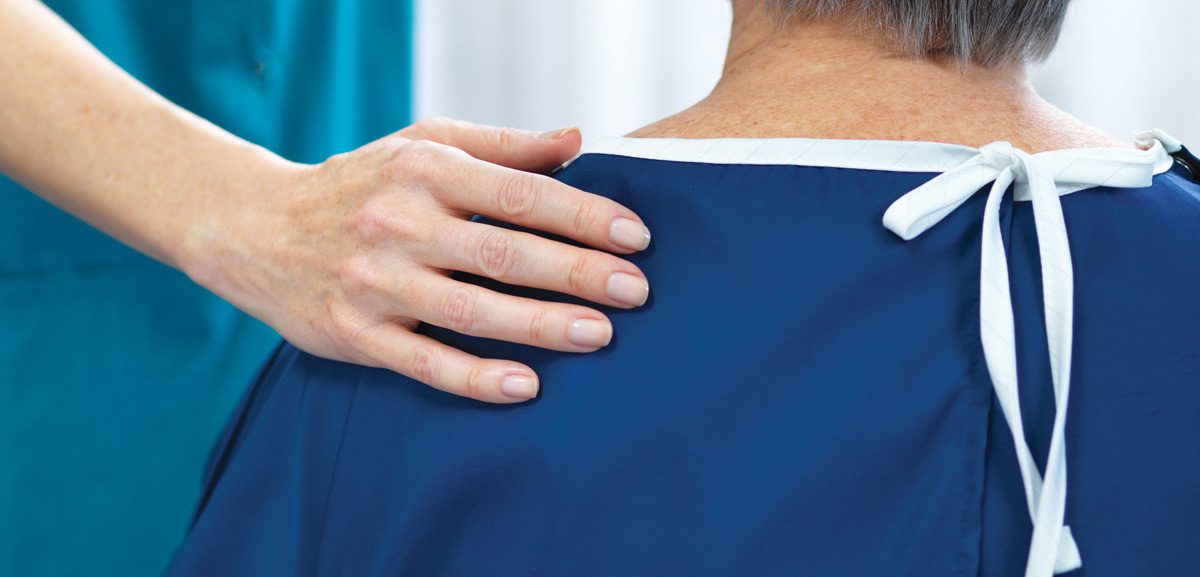Nurse putting her hand on the shoulder of a patient in a blue DermaTherapy® gown.