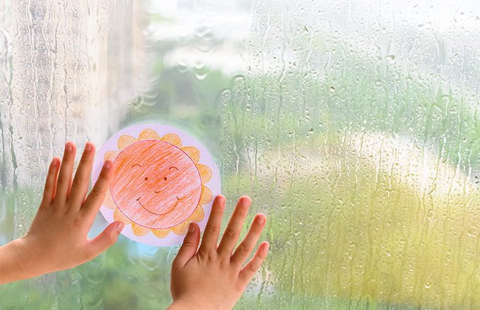 Child's hands on a crayon artwork on a window